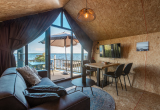 Cozy living room at Tiny House «Havenzicht» in the Netherlands, with lake view, patio, and modern decor.