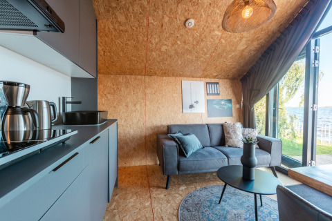 Cocina y sala modernas en Tiny House Havenzicht, con vistas al lago en De Wiedense Meren, Países Bajos.