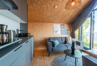 Modern kitchen and living area in Tiny House Havenzicht, overlooking the lake at De Wiedense Meren, Netherlands.