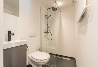 Baño moderno y compacto con ducha, inodoro y lavabo en Tiny House «Havenzicht» en De Wiedense Meren, Países Bajos.