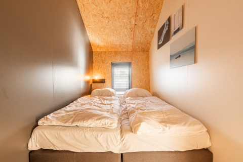 Cozy bedroom in Tiny House 'Havenzicht' with double beds and wood accents at De Wiedense Meren holiday park.