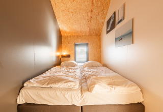 Cozy bedroom in Tiny House 'Havenzicht' with double beds and wood accents at De Wiedense Meren holiday park.