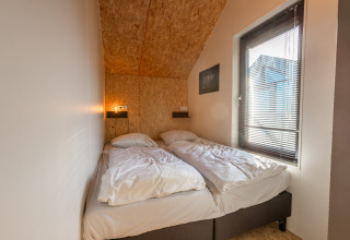 Dormitorio en Tiny House «Havenzicht» en Holiday park De Wiedense Meren con dos camas y una ventana.
