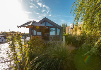 Tiny house moderne au bord de l’eau avec jardin luxuriant et parasol à De Wiedense Meren, Pays-Bas.