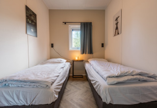 Deux lits simples avec literie blanche dans Holiday chalet Comfort, Holiday park De Wiedense Meren, Pays-Bas.