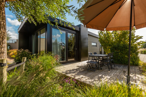 Terraza exterior con mesa, sillas y sombrilla en Holiday chalet Comfort, De Wiedense Meren, Países Bajos.