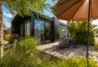 Terrasse extérieure avec table, chaises et parasol au Holiday chalet Comfort, De Wiedense Meren, Pays-Bas.