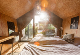 Solbeskinnet interiør i Tiny House på Holiday park De Wiedense Meren med udsigt til terrasse og natur.