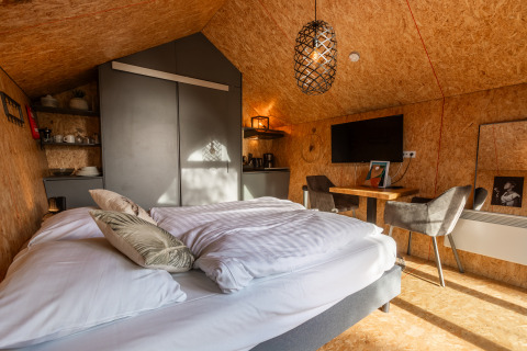 Interno della Tiny House al Holiday park De Wiedense Meren, con letto accogliente, tavolo e TV.