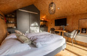 Binnenkant van de Tiny House op Holiday park De Wiedense Meren met bed, eettafel en tv.