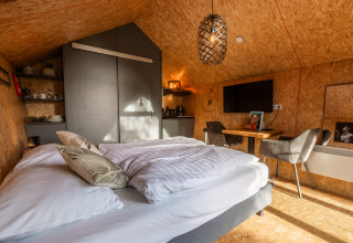 Indvendig billede af Tiny House ved Holiday park De Wiedense Meren, hyggeligt indrettet med seng og spisebord.