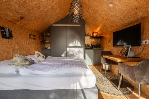 Tiny house accogliente al Holiday Park De Wiedense Meren, Paesi Bassi, con letto, scrivania e angolo cottura.