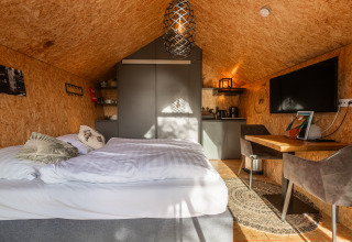 Tiny house accogliente al Holiday Park De Wiedense Meren, Paesi Bassi, con letto, scrivania e angolo cottura.