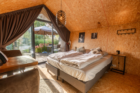 Tiny house accogliente a De Wiedense Meren con letto matrimoniale, pareti in legno e terrazza su giardino.