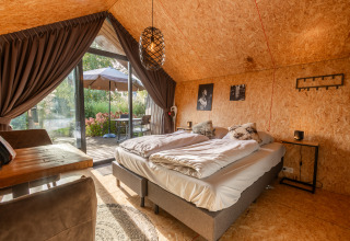 Tiny house accogliente a De Wiedense Meren con letto matrimoniale, pareti in legno e terrazza su giardino.