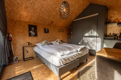 Modern lille hus med træpaneler, dobbeltseng, køkken og hyggelig indretning i De Wiedense Meren, Holland.