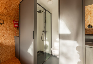 Moderne badeværelse i et tiny house ved Holiday park De Wiedense Meren i Holland med bruser og toilet.