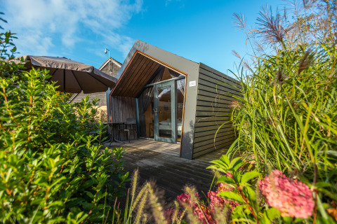 Tiny house moderna con terrazza in legno e grandi finestre, immersa nel verde a De Wiedense Meren, Paesi Bassi.