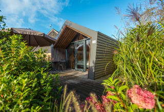 Tiny house moderna con terrazza in legno e grandi finestre, immersa nel verde a De Wiedense Meren, Paesi Bassi.