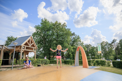 Bambini che giocano nel parco ricreativo Kaps a Overijssel, Paesi Bassi, con adulti nei pressi.