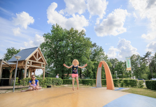 Kinder spielen auf einem Spielplatz im Ferienpark Kaps in Overijssel, Niederlande, bei sonnigem Wetter.
