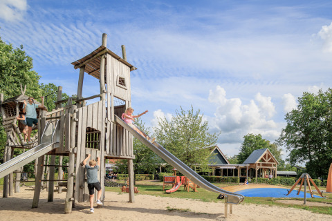 Children playing on a large wooden playground with slides at holiday park Kaps in Overijssel, Netherlands.
