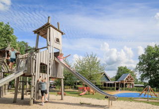 Children playing on a large wooden playground with slides at holiday park Kaps in Overijssel, Netherlands.