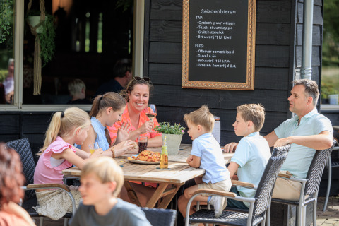 Una famiglia si gode cibo e bevande all’aperto nel parco vacanze Kaps a Overijssel, Paesi Bassi.