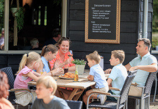 Una famiglia si gode cibo e bevande all’aperto nel parco vacanze Kaps a Overijssel, Paesi Bassi.