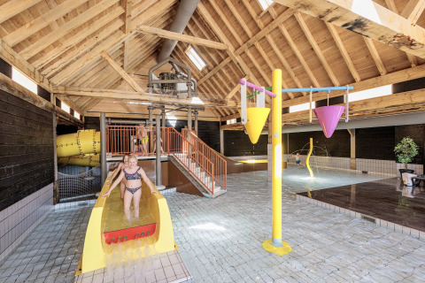 Innen-Wasserspielplatz im Ferienpark Kaps in Overijssel, Niederlande, mit Kindern und Wasserrutsche.