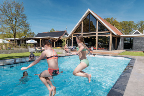 Kinder springen in den Pool im Erholungspark Kaps in Overijssel, Niederlande, an einem sonnigen Tag.