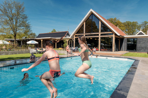 Kinder springen in den Pool im Erholungspark Kaps in Overijssel, Niederlande, an einem sonnigen Tag.