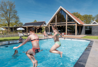 Kinder springen in den Pool im Erholungspark Kaps in Overijssel, Niederlande, an einem sonnigen Tag.