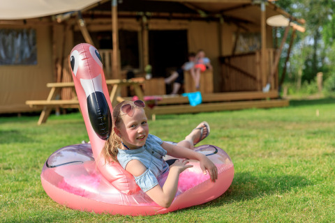 Ragazza si rilassa su un fenicottero gonfiabile davanti alla tenda Safari Appelgaard al parco Kaps, Paesi Bassi.