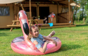 Ragazza si rilassa su un fenicottero gonfiabile davanti alla tenda Safari Appelgaard al parco Kaps, Paesi Bassi.