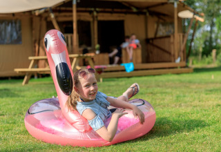 Ragazza si rilassa su un fenicottero gonfiabile davanti alla tenda Safari Appelgaard al parco Kaps, Paesi Bassi.
