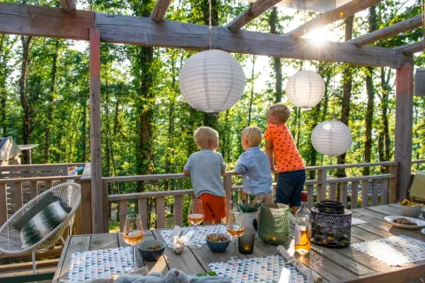 Des enfants profitent d’un repas en terrasse avec lanternes au Chianti Glamping Resort, Toscane, Italie.
