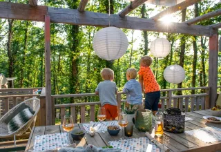 Kinder genießen ein Abendessen im Freien auf einer Terrasse mit Laternen im Chianti Glamping Resort, Toskana.