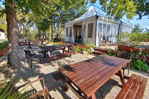 Area pranzo all'aperto con tavoli e panche in legno presso il Campeggio Village Mare Pineta, Friuli-Venezia Giulia.