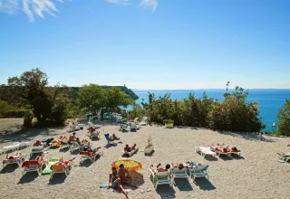 Ospiti che prendono il sole su lettini al mare al campeggio Village Mare Pineta a Friuli Venezia Giulia, Italia.