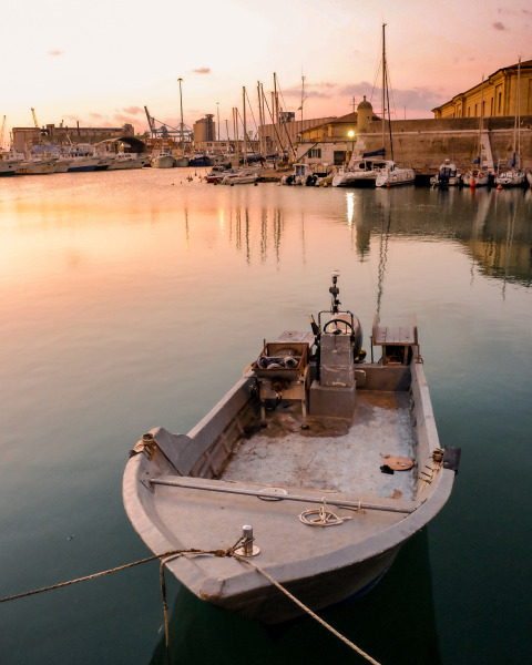 Piccola barca ormeggiata in un porto tranquillo al tramonto vicino a Sistiana, Friuli-Venezia Giulia, Italia.