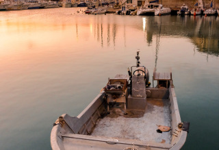 A small boat moored in a peaceful harbor at sunset near Sistiana, Friuli-Venezia Giulia, Italy.
