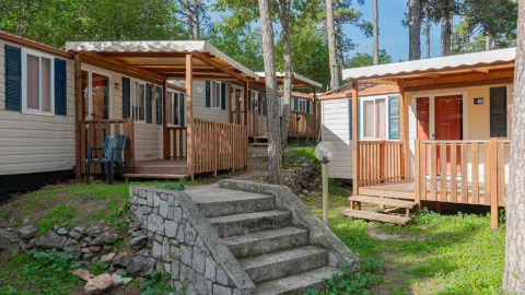 Case mobili con verande in legno nel verde del Campeggio Village Mare Pineta, Friuli-Venezia Giulia, Italia.
