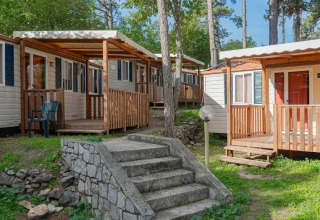 Case mobili con verande in legno nel verde del Campeggio Village Mare Pineta, Friuli-Venezia Giulia, Italia.