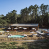 Huttopia Caminos de Galicia glamping site featuring a pool area, sun umbrellas, wooden deck, and forest view.
