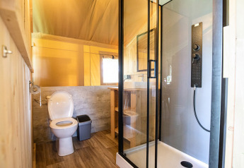 Moderne badeværelse i safaritelt med bruser, toilet og træinteriør på Hameau de l'Ourthe, Belgien.