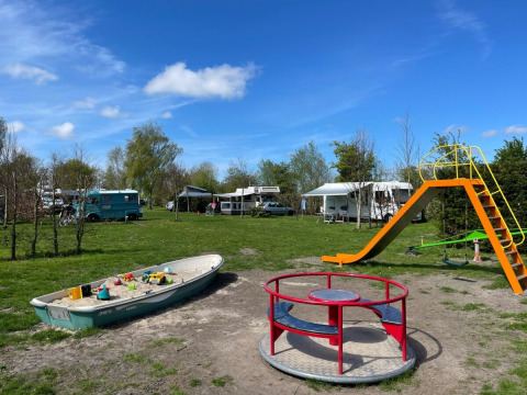 Playground at de Boerenzwaluw campsite, North Holland, with a slide, roundabout, and boat sandpit.