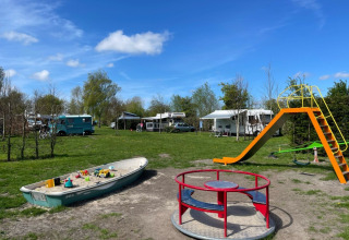 Playground at de Boerenzwaluw campsite, North Holland, with a slide, roundabout, and boat sandpit.
