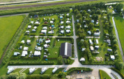 Aerial view of Campsite de Boerenzwaluw in North Holland, Netherlands, showing campers, caravans, and greenery.
