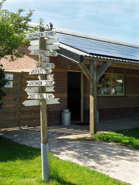 Wooden signpost with distances to local destinations at campsite de Boerenzwaluw, North Holland, Netherlands.